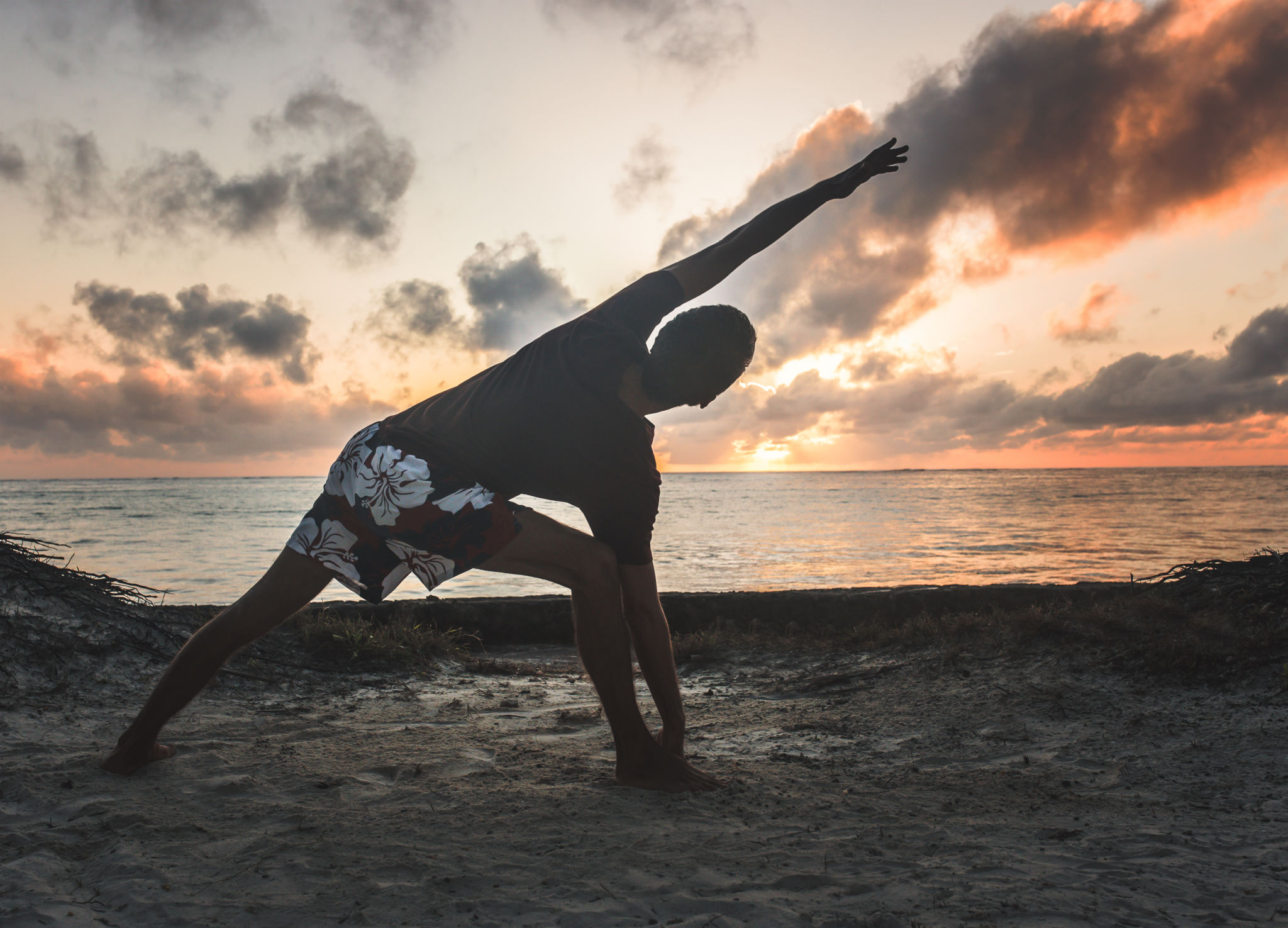 Practicing yoga and meditation in summer on beach in sunset